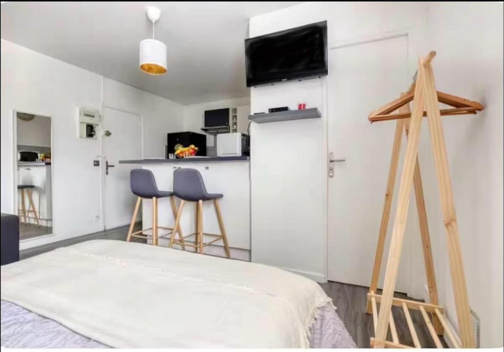 une chambre avec deux tabourets et une cuisine avec un réfrigérateur dans l'établissement 1 Studio cozy a 30 minutes de Paris centre, à Houilles