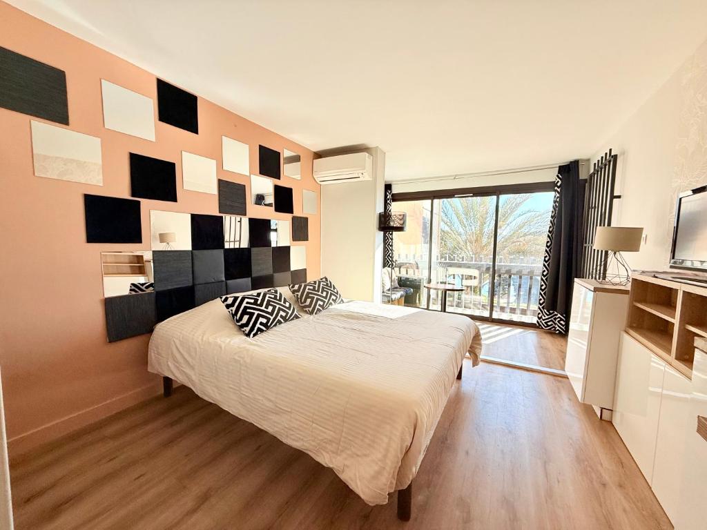 une chambre avec un grand lit et une grande fenêtre dans l'établissement Village Naturiste - La Venus - Parking WiFi, au Cap d'Agde