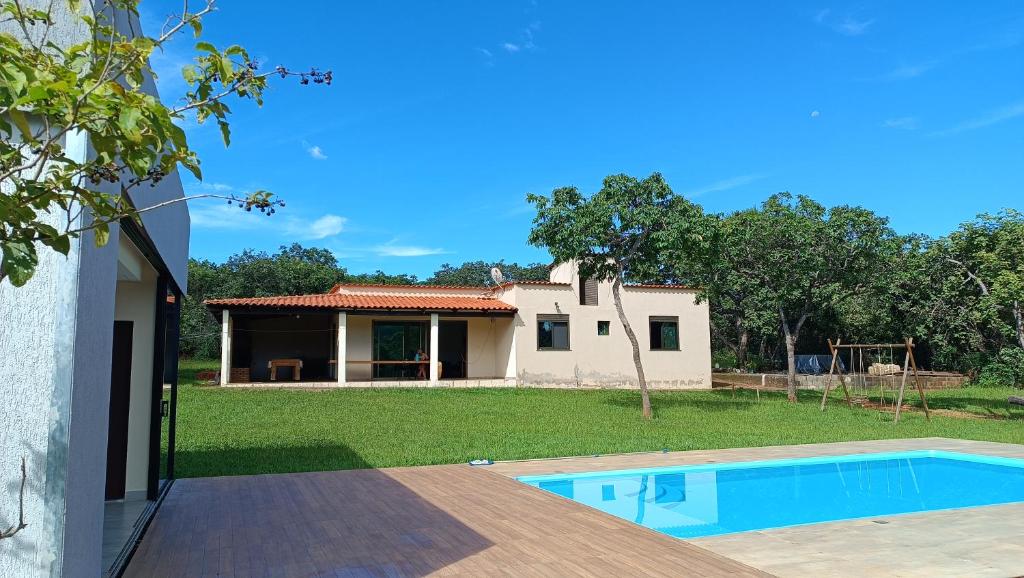 a house with a swimming pool in front of a yard at Casa de campo Serra do Cipó in Serra do Cipo