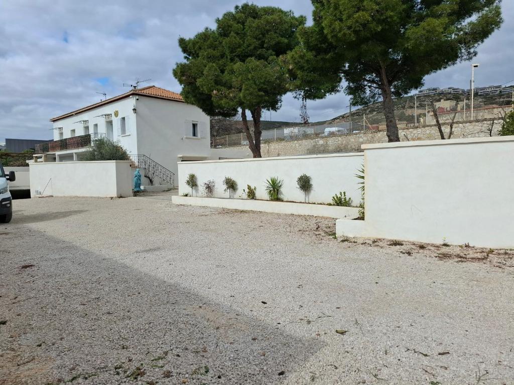 une clôture blanche avec des arbres devant un bâtiment dans l'établissement Havre de paix, à Marseille