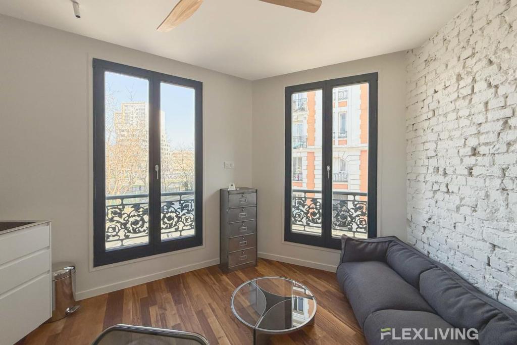 un salon avec un canapé et deux fenêtres dans l'établissement Superb spacious apartment located at Mont Cenis, à Paris