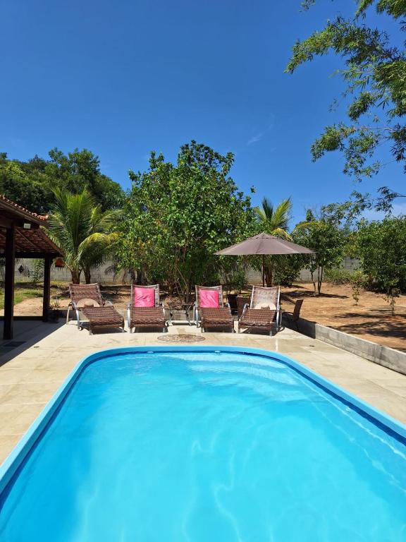 a swimming pool with chairs and an umbrella at Pouso Zen in Araruama