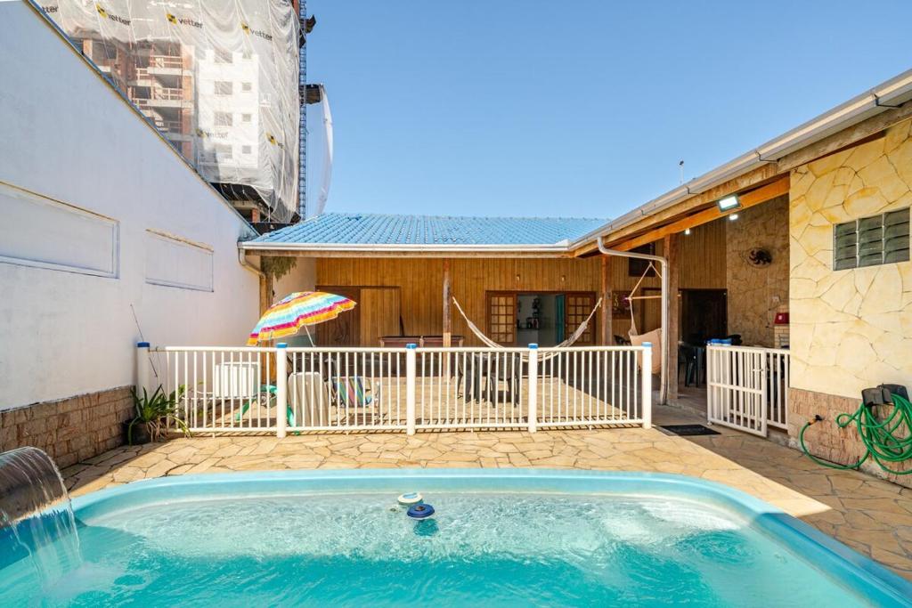 ein Swimmingpool mit Sonnenschirm und ein Haus in der Unterkunft Piscina e mar em único lugar in Penha