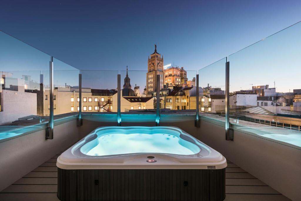 a hot tub on a balcony with a view of the city at Catalonia Gran Vía Madrid in Madrid