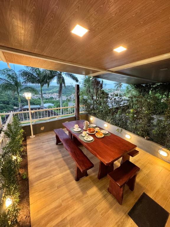 a wooden table and benches on a balcony with a view at Apartamento de um quarto com varanda externa in Bananeiras