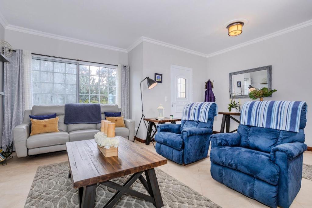 a living room with blue chairs and a table at La Casita Felizola- Charming Coastal Escape in São Pedro