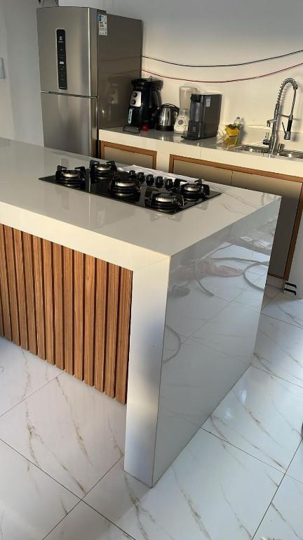 a kitchen with a white counter with a stove top at Casa da Marília in Porto Seguro