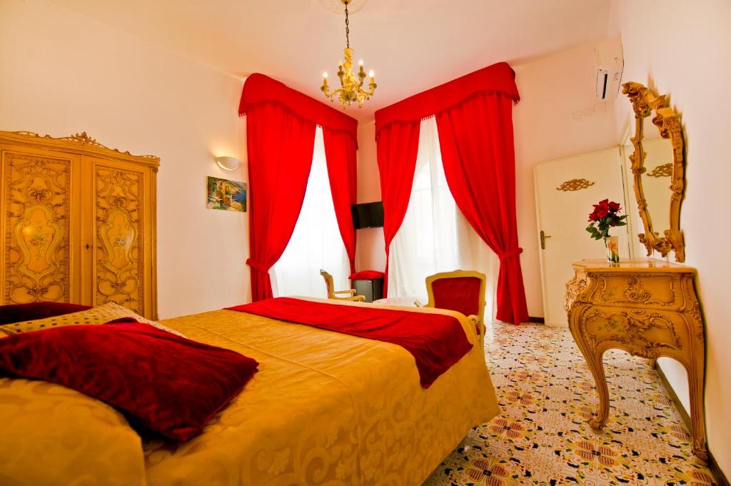 a bedroom with red curtains and a bed and a dresser at Residenza Sole Amalfi in Amalfi