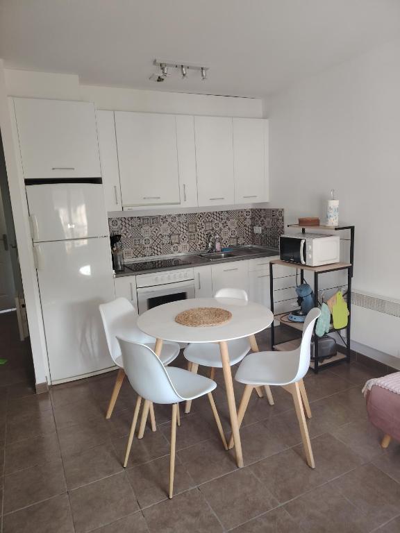 une cuisine avec une table et des chaises et une table et un comptoir dans l'établissement Castèléma - Appartement proche du sanctuaire, à Lourdes