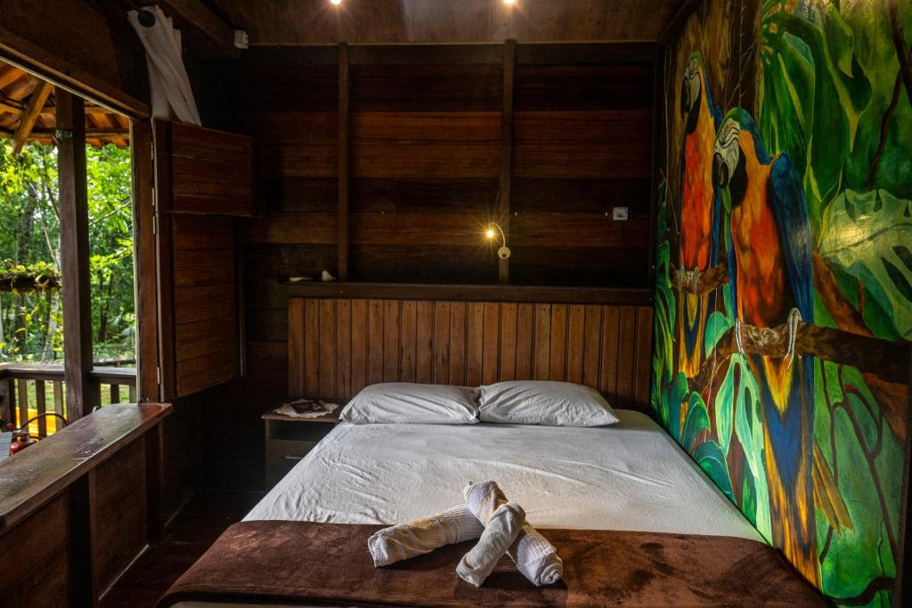 a bed in a room with a painting on the wall at TerrAmor Ecoliving in Alter do Chao