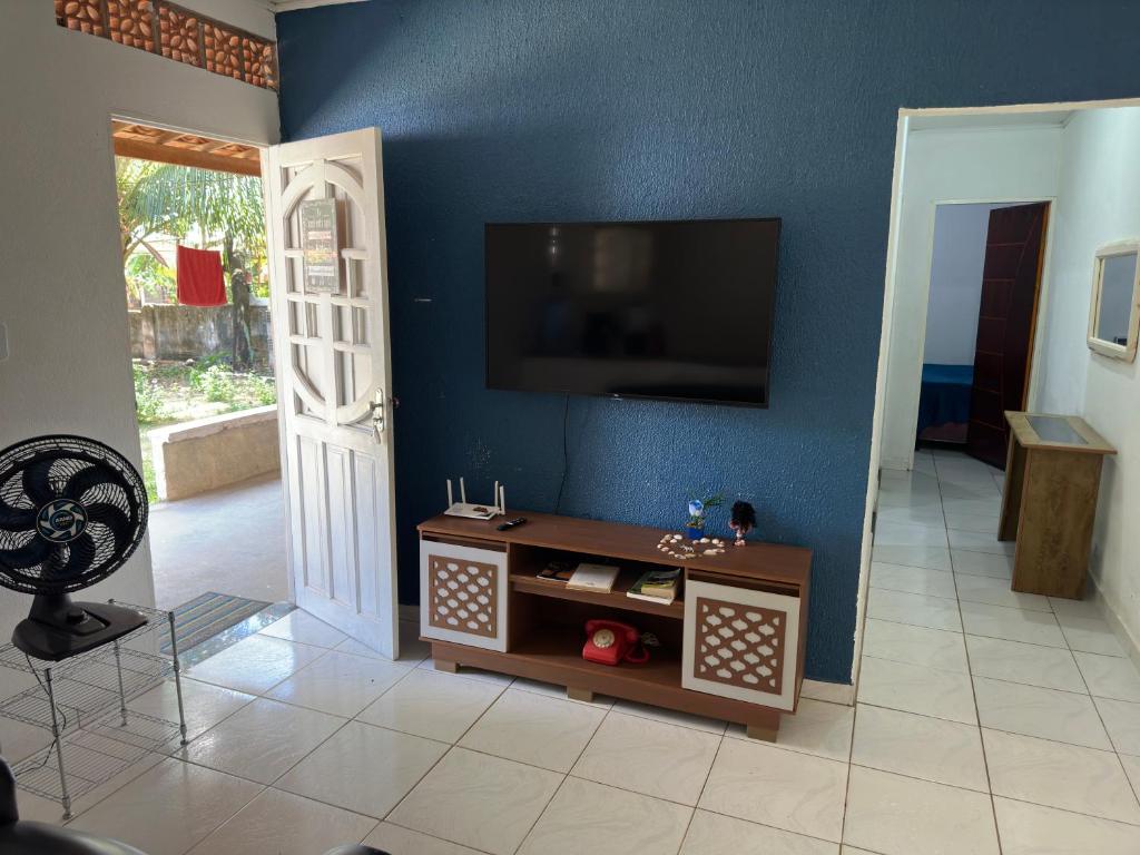 a living room with a tv on a blue wall at Casa 01 simples e aconchegante em Maragogi in Maragogi