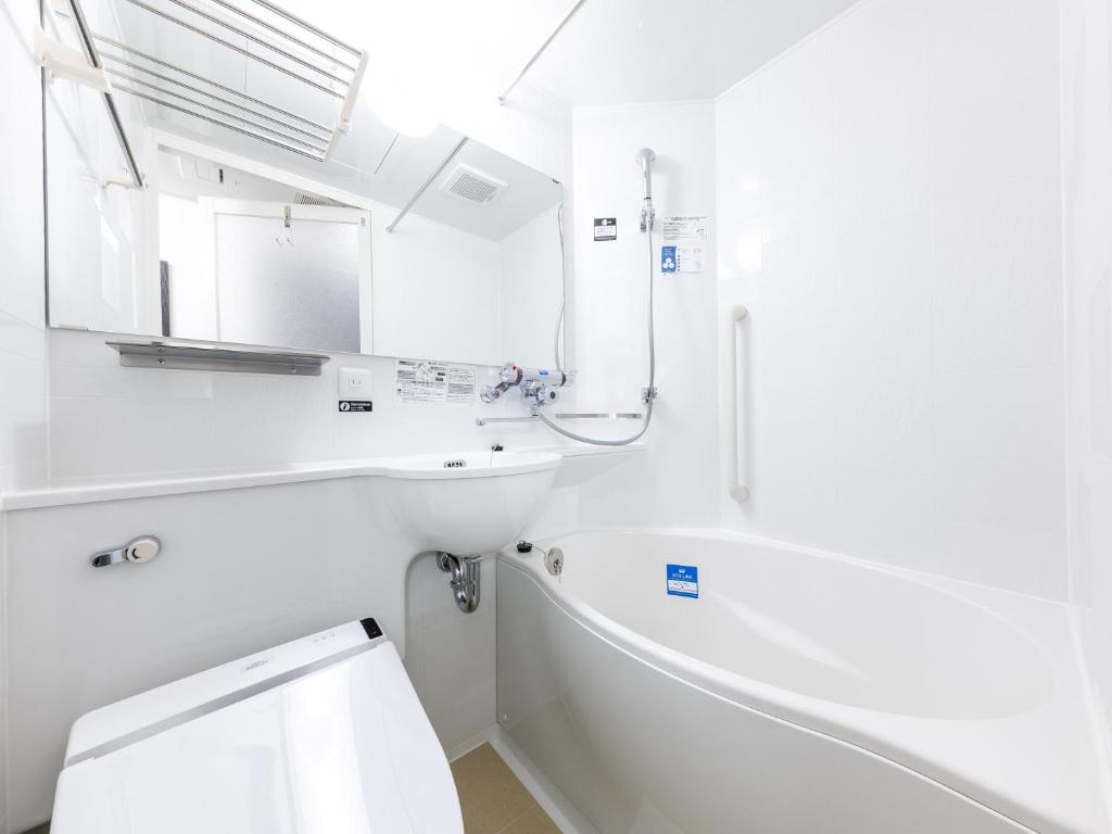 a white bathroom with a tub and a sink at APA Hotel Shibuya Dogenzakaue in Tokyo