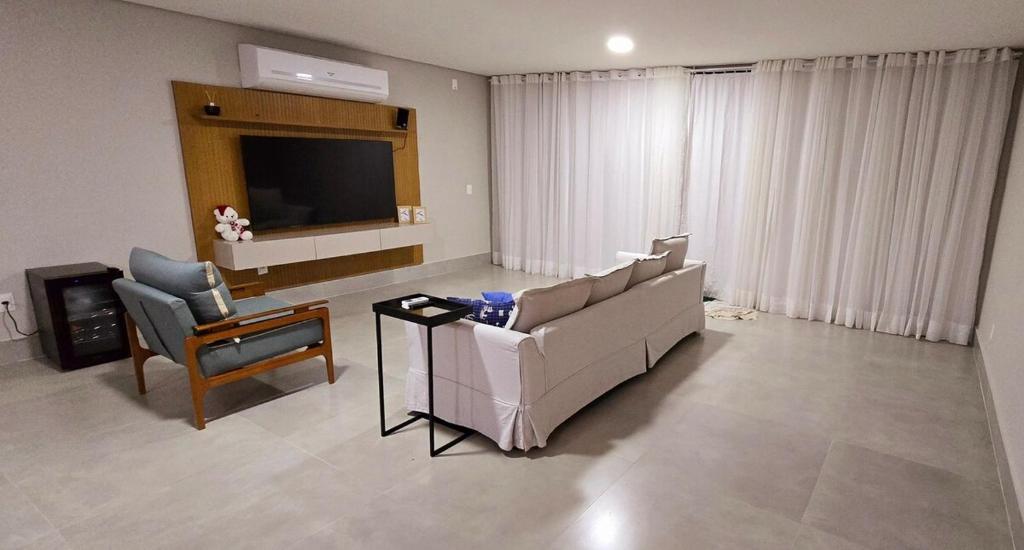 ein Wohnzimmer mit einer Couch und einem Sessel in der Unterkunft Maravilhosa casa linear 5 suítes em Angra in Angra dos Reis