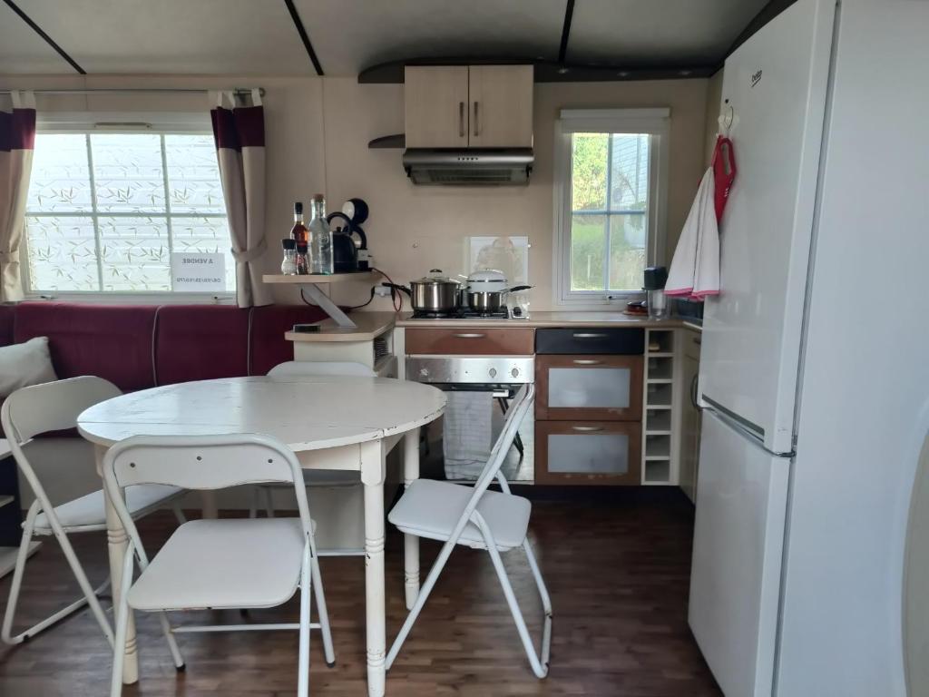 une petite cuisine avec une table et des chaises blanches dans l'établissement Mobilhome résidentiel, à Gassin