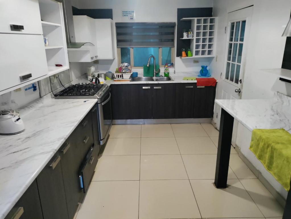 San AntonioにあるCasa de Huéspedes Encanto Raramuriのキッチン(黒いキャビネット、白いカウンタートップ付)