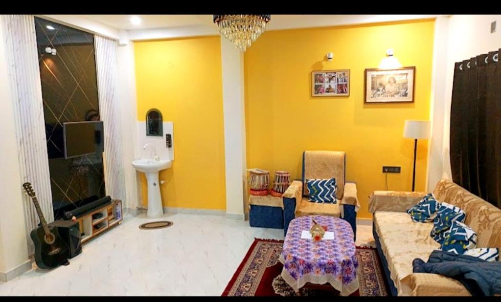 sala de estar con paredes amarillas, sofá y lavamanos en Bajrang kutir 1, en Varanasi