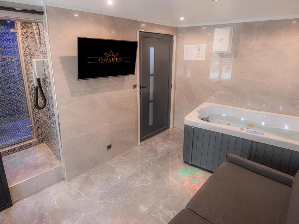 La salle de bains est pourvue d'une baignoire et d'une télévision murale. dans l'établissement Le lovely - Spa & Jacuzzi, à Manosque
