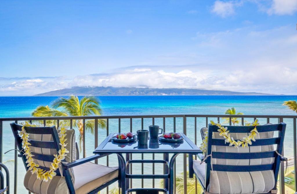 een tafel en stoelen op een balkon met uitzicht op de oceaan bij Valley Isle Resort 804 condo in Kahana