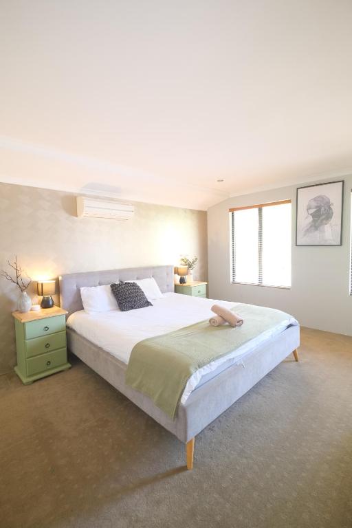 ein Schlafzimmer mit einem großen weißen Bett und einem Fenster in der Unterkunft Airport 5BR Retreat - Full Kitchen & Tranquil in Perth