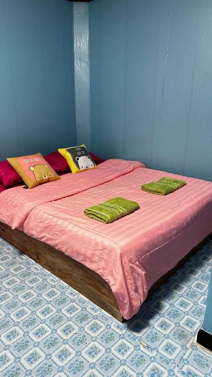 a large bed with pink sheets and green pillows at KohLibong Beach House Homestay in Ban Batubute