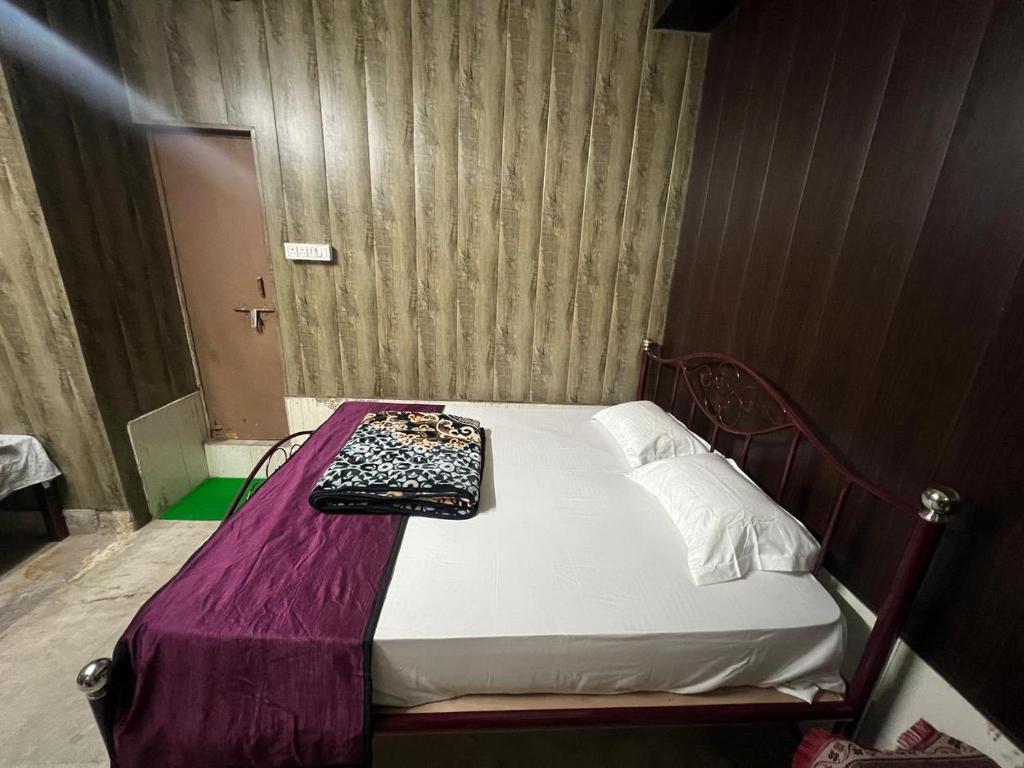 a small bed in a room with a purple sheet at Triveni Sangam Homestay in Prayagraj