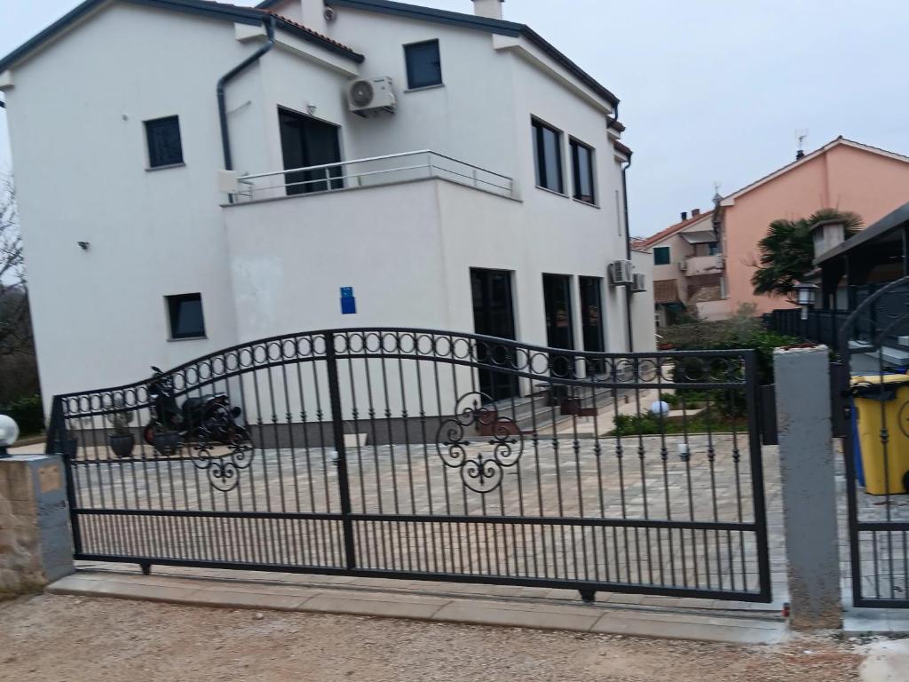 a white house with a gate in front of it at IGGY in Malinska