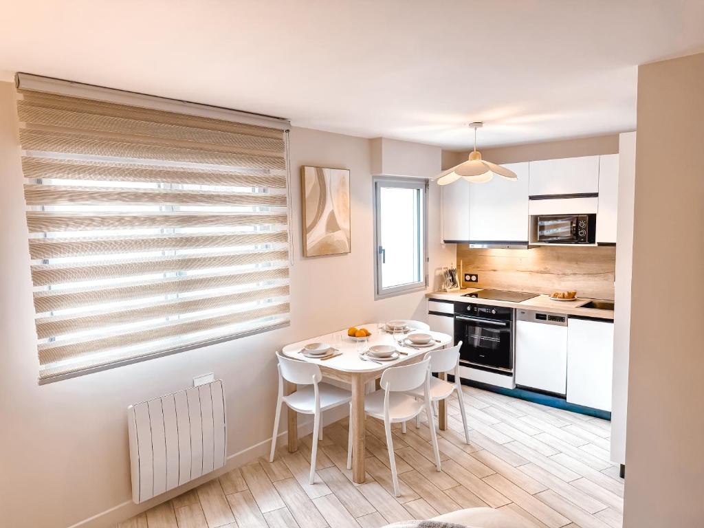 une petite cuisine avec une table et des chaises blanches dans l'établissement Grand Studio au coeur de Deauville I La Place de Morny et La Gare sont à 5 min à pied, à Deauville