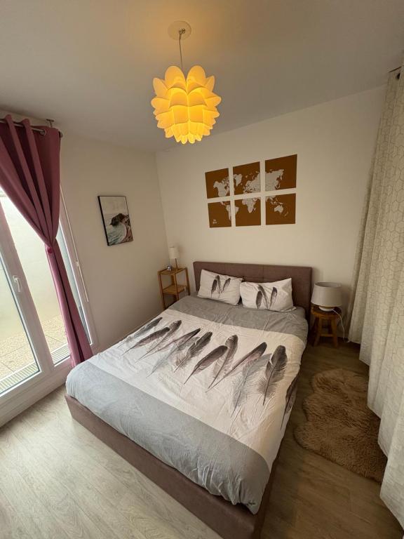 ein Schlafzimmer mit einem großen Bett und einem Kronleuchter in der Unterkunft Nouveau F2 au calme proche Paris in Montigny-lès-Cormeilles