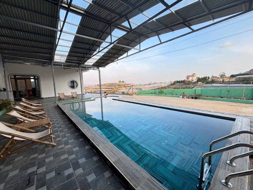 une grande piscine avec des chaises longues et une grande fenêtre dans l'établissement Villa Healing Home Hồ Bơi Nước Nóng, à Trai Mat