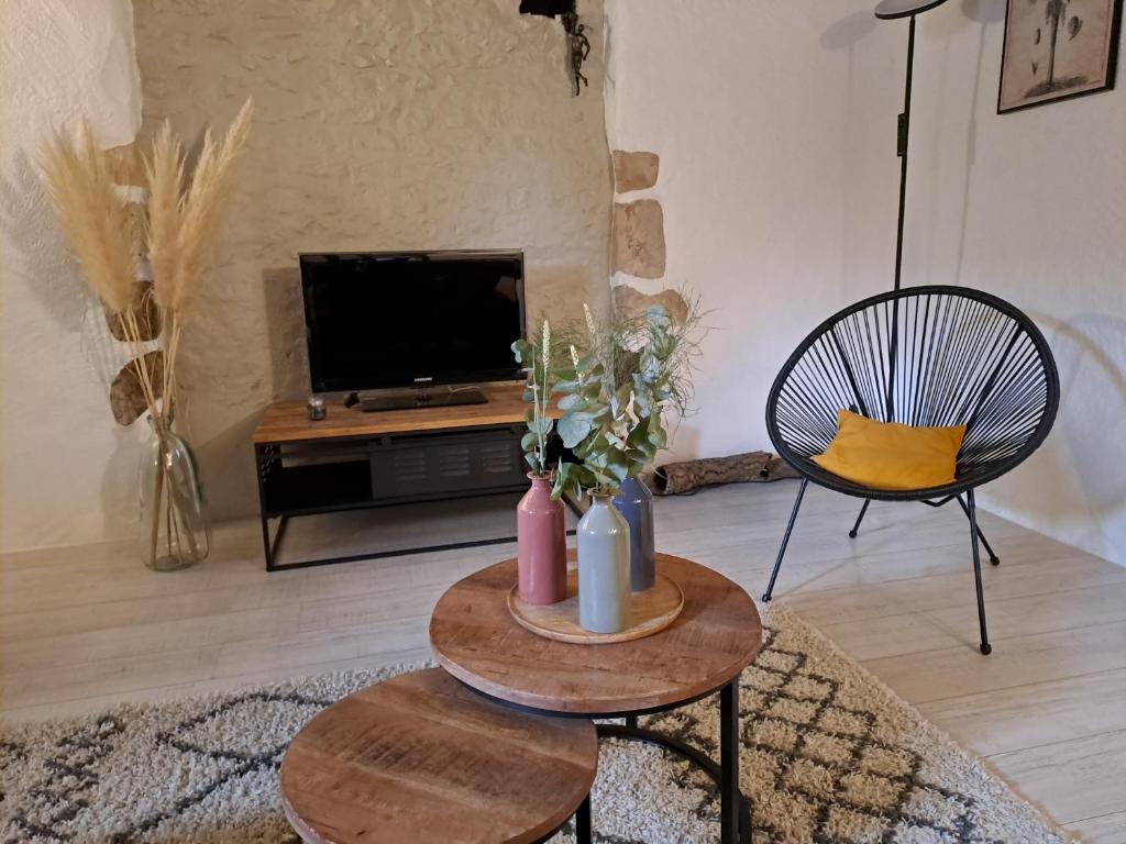 un salon avec une table et une télévision dans l'établissement La Chaumière de Chabine, à Oizon