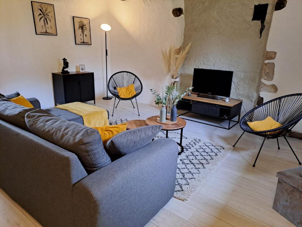 ein Wohnzimmer mit Sofa, Sesseln und Fernseher in der Unterkunft La Chaumière de Chabine in Oizon
