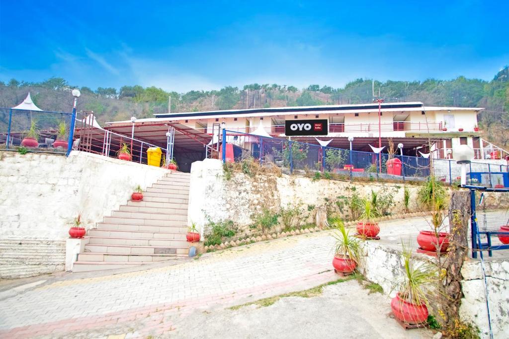 a building with stairs and potted plants in front of it at Hotel Kalka And Restaurant Patnitop in Kūd