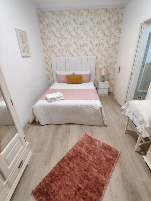 Un dormitorio con una cama blanca con una alfombra roja. en casa saloia, en Nazaré