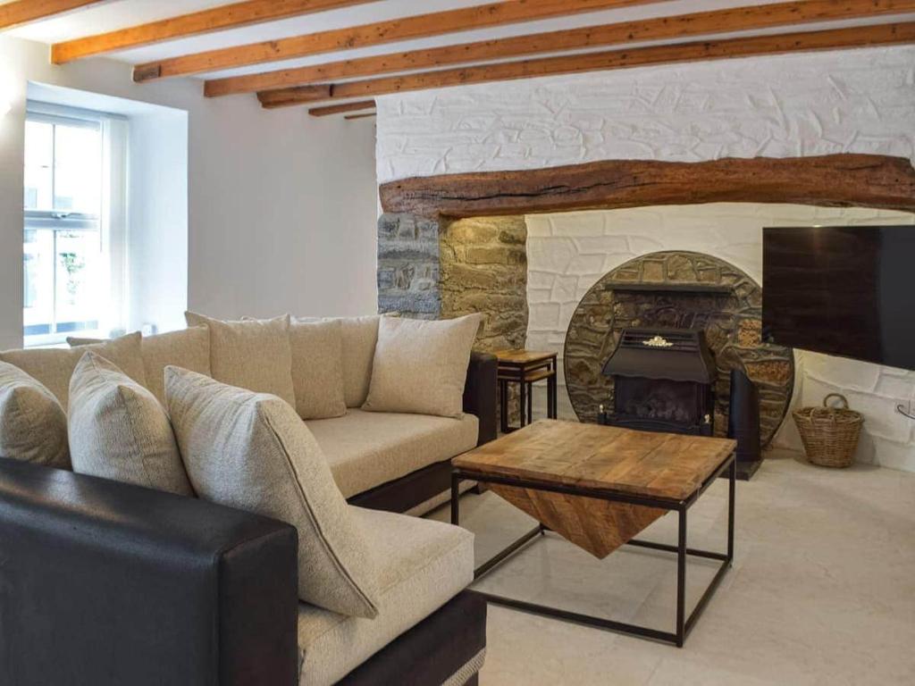 ein Wohnzimmer mit Sofa und Kamin in der Unterkunft Hideaway Cottage in Troedyraur