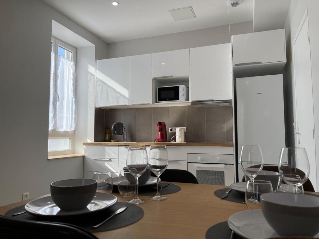 una cucina con tavolo e bicchieri da vino di Appart'Village Le vieux Vichy centre T1,T2,T3 - Parking - Thermes a Vichy