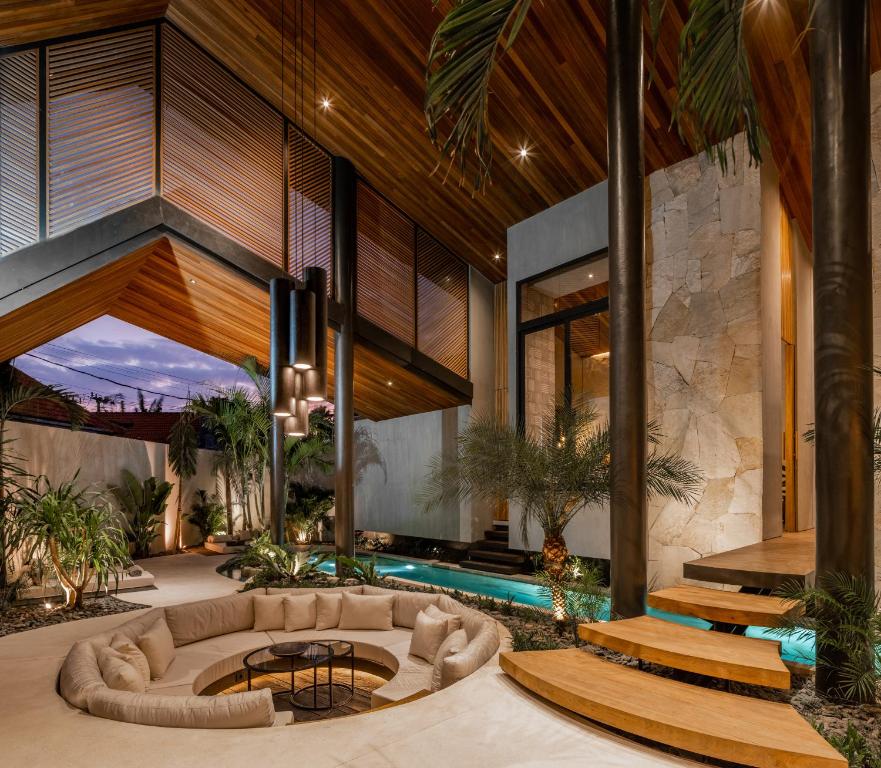 Una sala de estar interior con un sofá y una piscina. en Villa Levante Bali by House of Winds - Tropical Oasis near Canggu, en Kerobokan