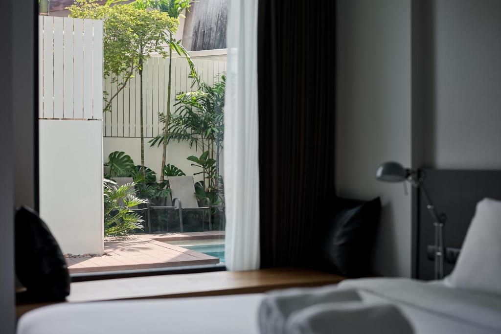 A bedroom looking through a large window toward a planted poolside courtyard.