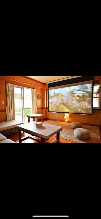 a living room with a table and a large painting on the wall at 南国リゾートBari Okinawa in Itoman