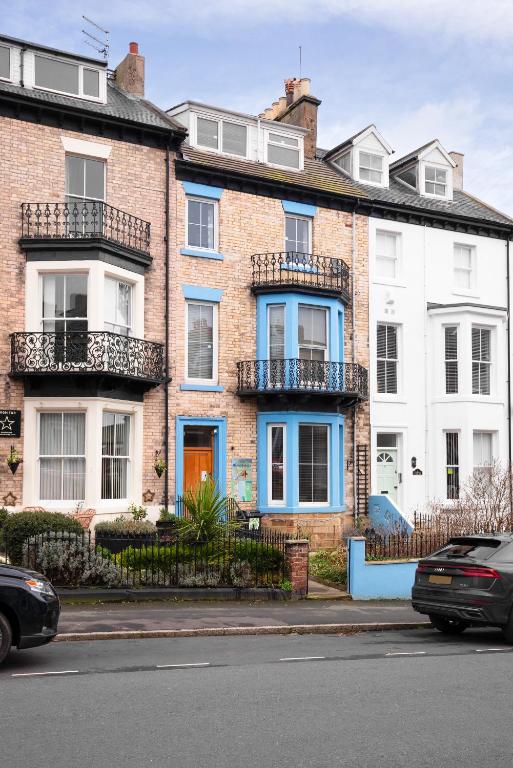 a brick building with blue windows and balconies on a street at Beach House in Whitby