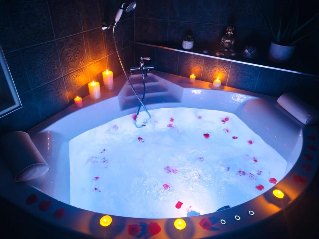 Una bañera con velas en una habitación. en La jungle insolite, SPA, Écran cinéma, Lit à baldaquin king size, day use, 10 min centre, en Amiens