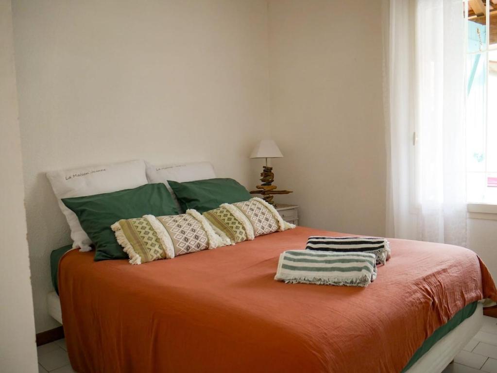 - un lit avec une couverture orange et des oreillers dans l'établissement La Maison Jeanne, Portiragnes Plage, à Portiragnes