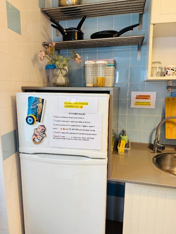 a refrigerator in a kitchen with a sign on it at 70's Hostel in Ericeira