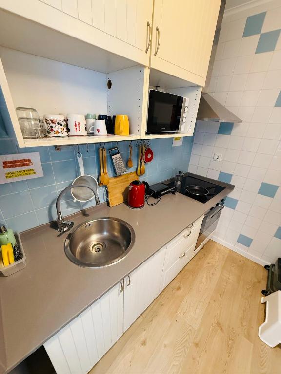 a small kitchen with a sink and a microwave at 70's Hostel in Ericeira