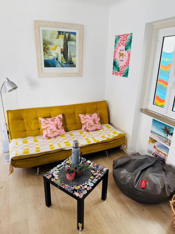 a living room with a yellow couch and a table at 70's Hostel in Ericeira