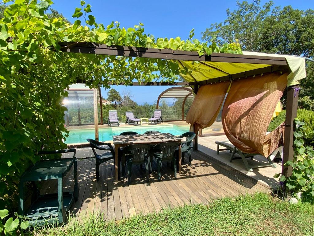 eine Terrasse mit Tisch und Stühlen und einem Pool in der Unterkunft Maison au calme piscine mer au coeur de la nature U Nuciolu in Talasani