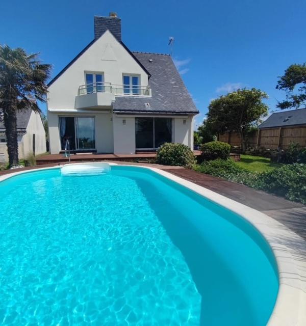 une grande piscine bleue devant une maison dans l'établissement Maison spacieuse avec piscine, à Guidel