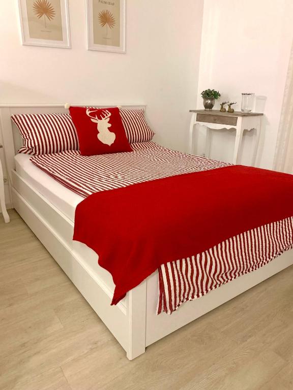 a bed with a red and white blanket on it at Ferienwohnung Pipergast mit Terrasse in Oerlinghausen