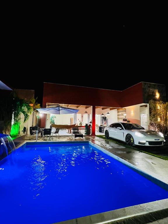 a blue pool in front of a house at night at Alcobaça Beach House in Alcobaça