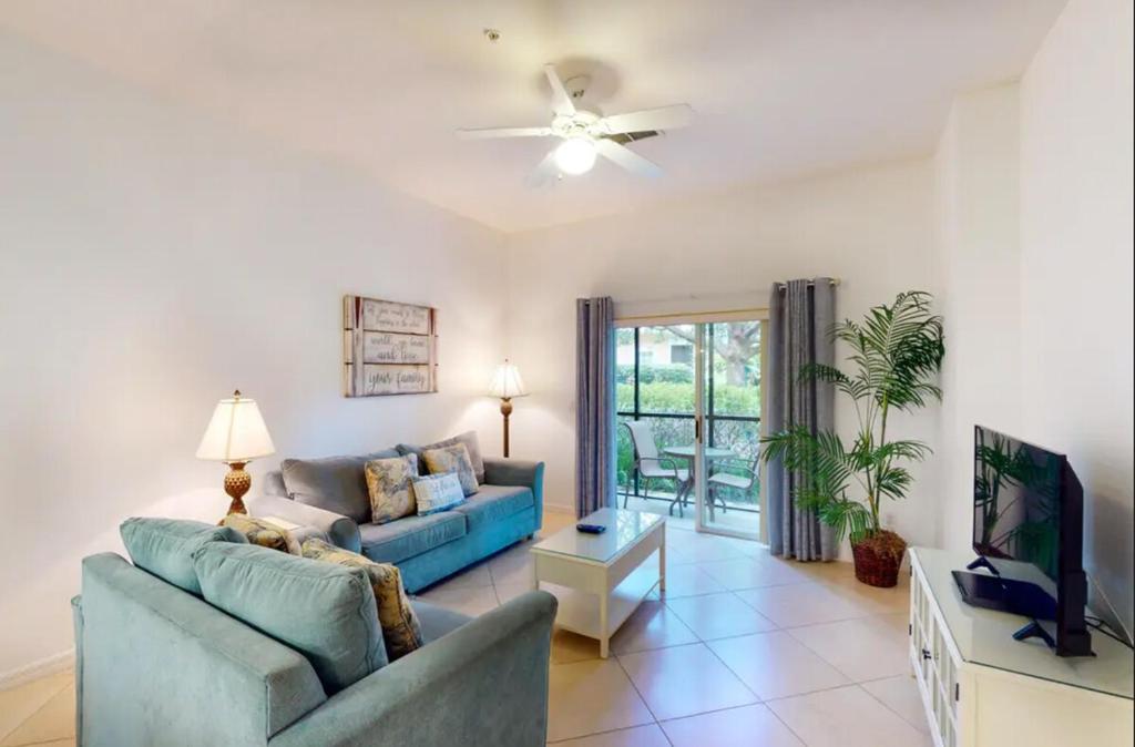 Una sala de estar con un sofá azul y un televisor en 3 Bedroom Condo In Fabulous Resort Near Disney World, en Kissimmee