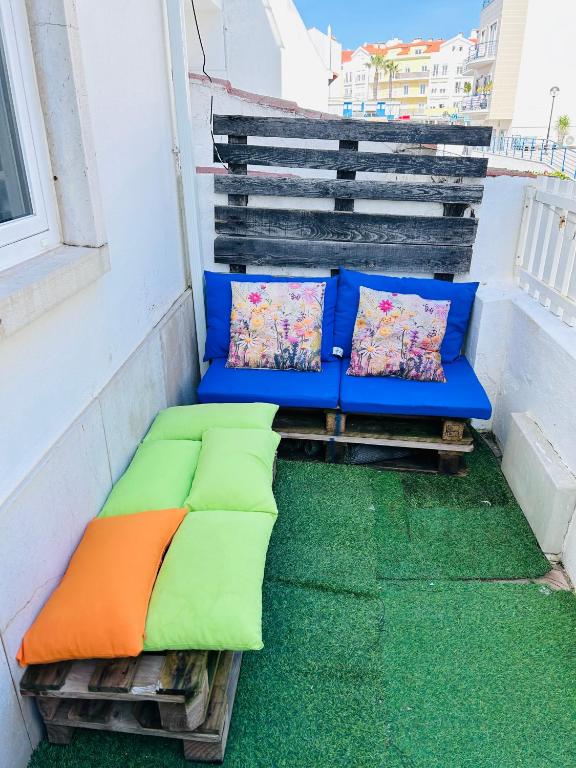a couch with pillows sitting on a balcony at 70's Hostel in Ericeira